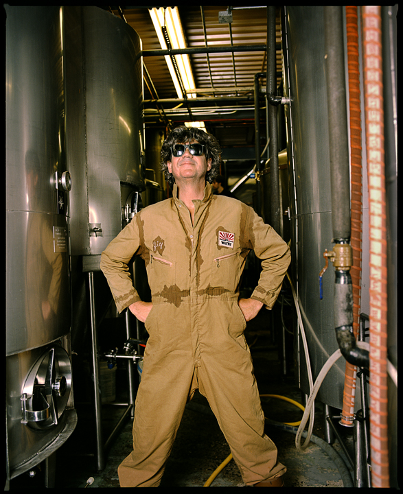 Person in tan flight suit posing in brewery fermentation tank room, Ray Deter benefit event, 2011