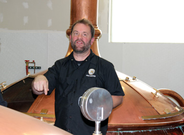 Brewer at Prost brewery standing beside copper brewing vessel, circa 2012