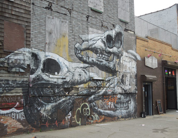 Skeletal dinosaur skull street art mural on Bushwick building wall, circa 2012