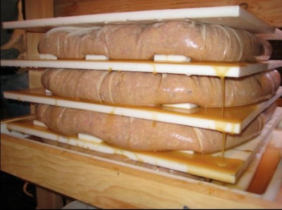 Stacked wooden cider press plates with apples being pressed, circa 2011