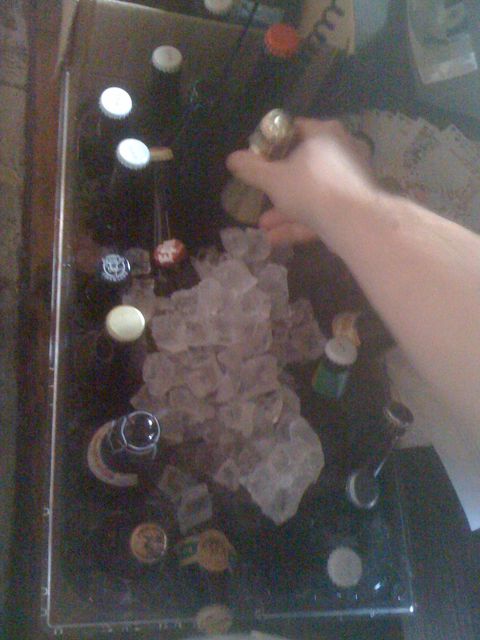 Hand reaching toward multiple beer bottles arranged on a table at Beer Sessions Radio, circa 2010