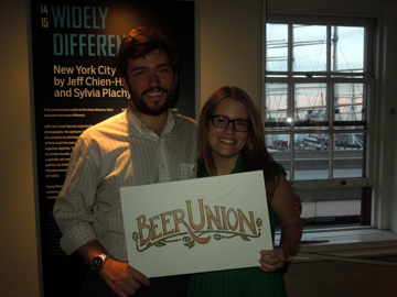 Two people holding Beer Union logo at Beer Book, Blog & Video Fest, South Street Seaport Museum, 2012